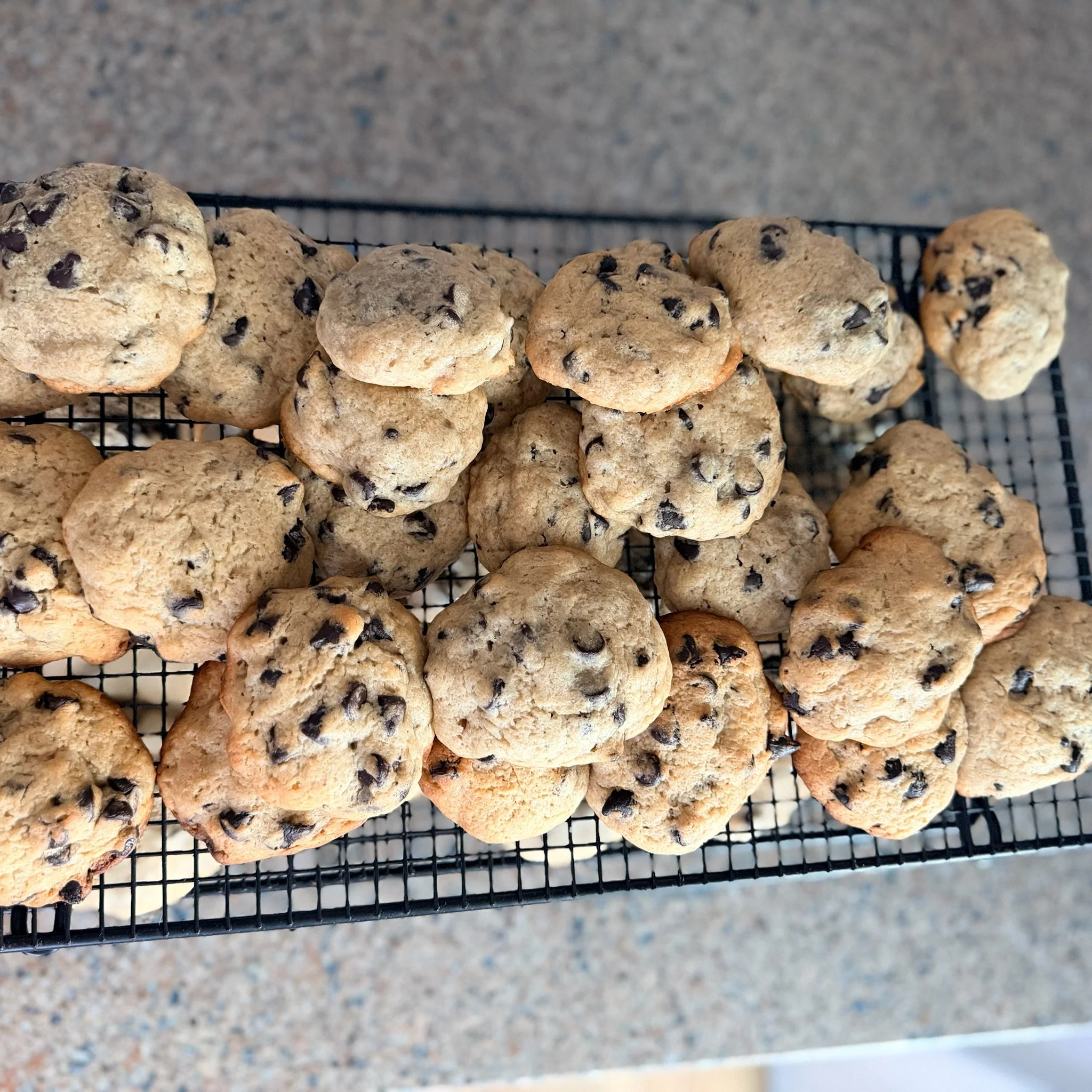 Close-up of chocolate chip cookies on a wire cooling rack on a speckled countertop.