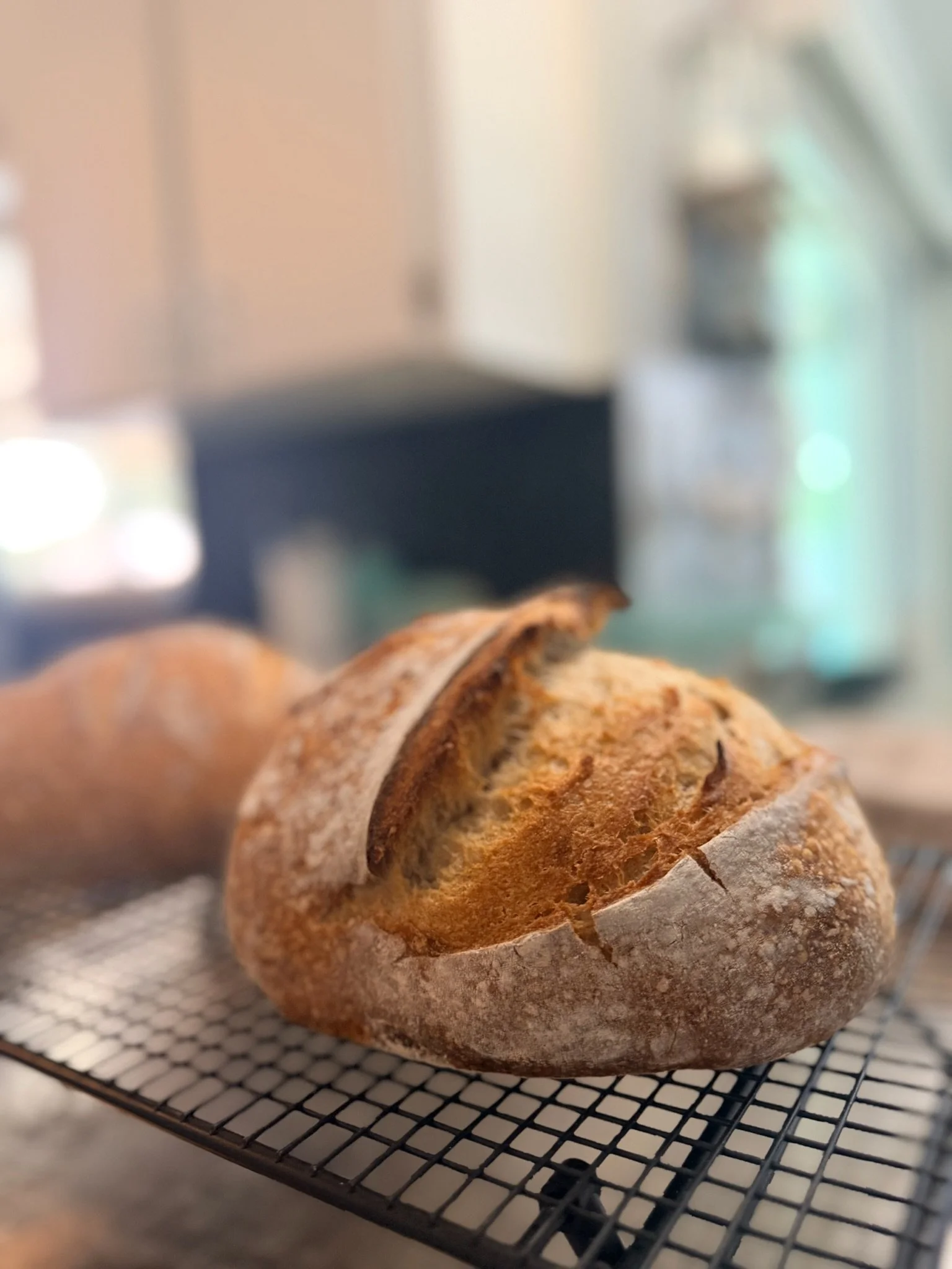 A loaf of bread cooling on a wire rack in a kitchen.