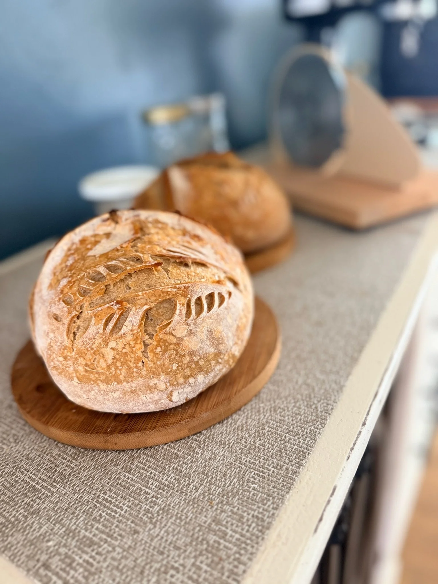 Close-up of freshly baked Italian bread on a wooden cutting board, placed on a textured tablecloth.