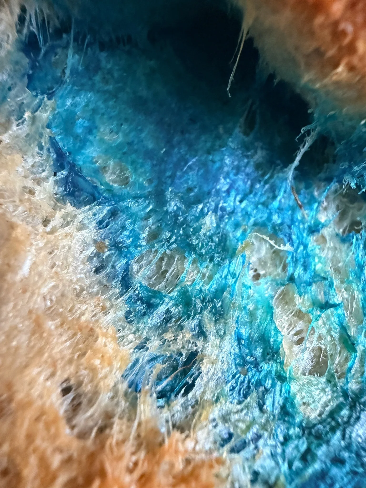 Close-up view of a colorful mix of blue and beige textures, resembling the inside of a crystal or mineral formation.