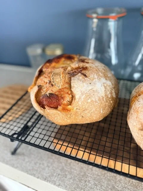 Freshly baked bread roll with visible chunks of pepperoni and cheese on a cooling rack.