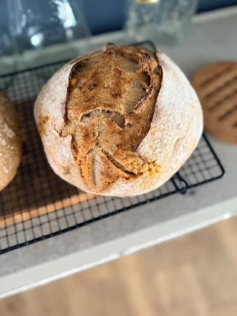 Close-up of a round, rustic bread or pastry with a cracked top, resting on a cooling rack.