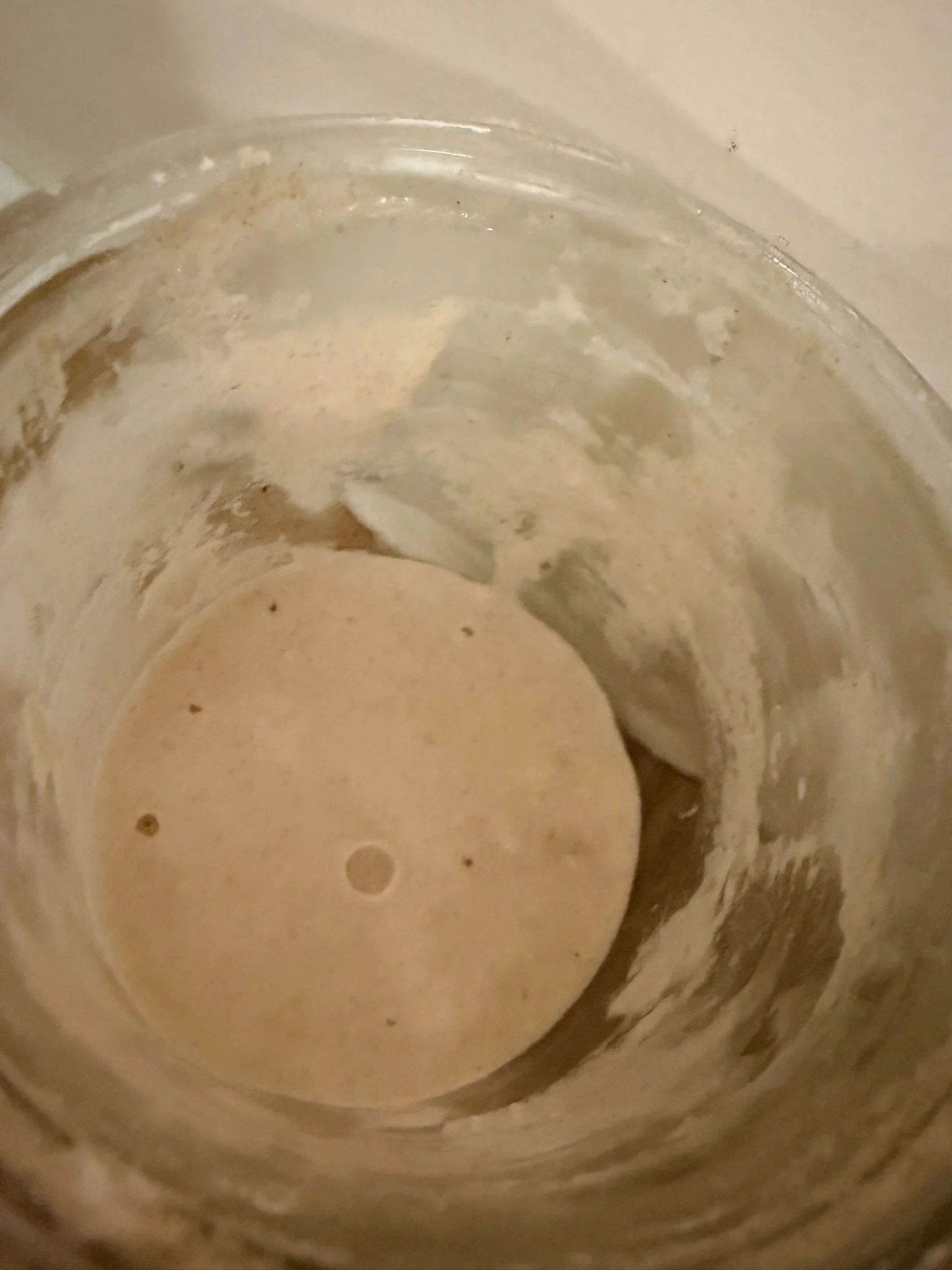 A close-up view inside a cylindrical metal container with a beige, foamy substance at the bottom.