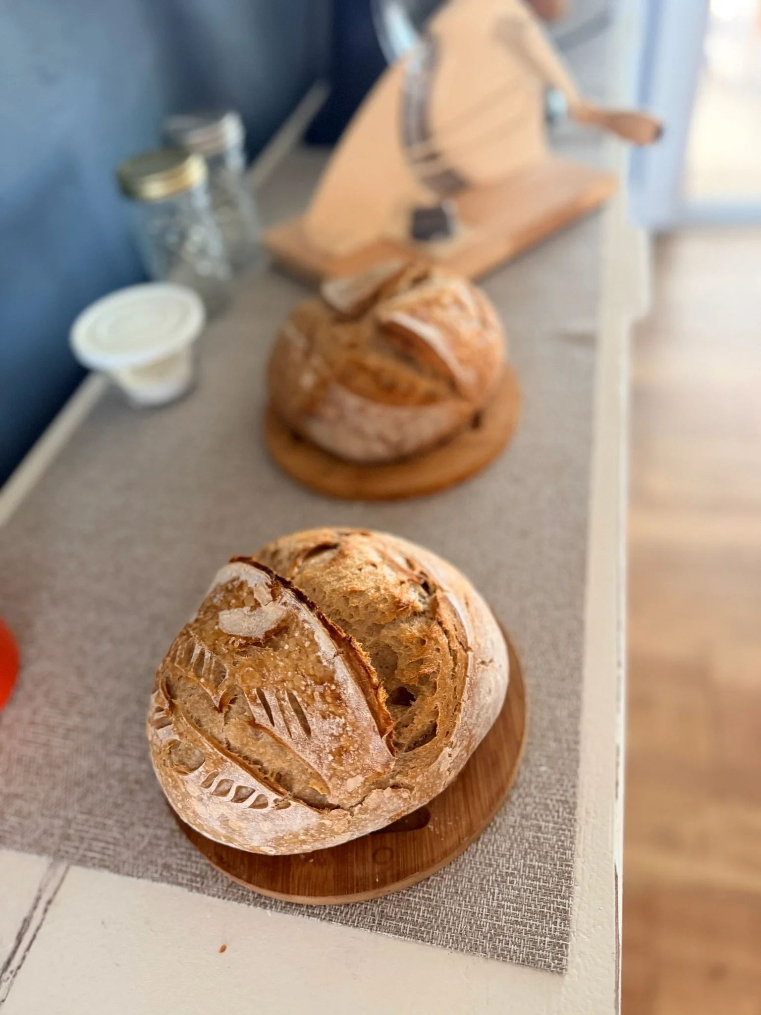 Round loaf of bread with a crusty exterior on a wooden cutting board.