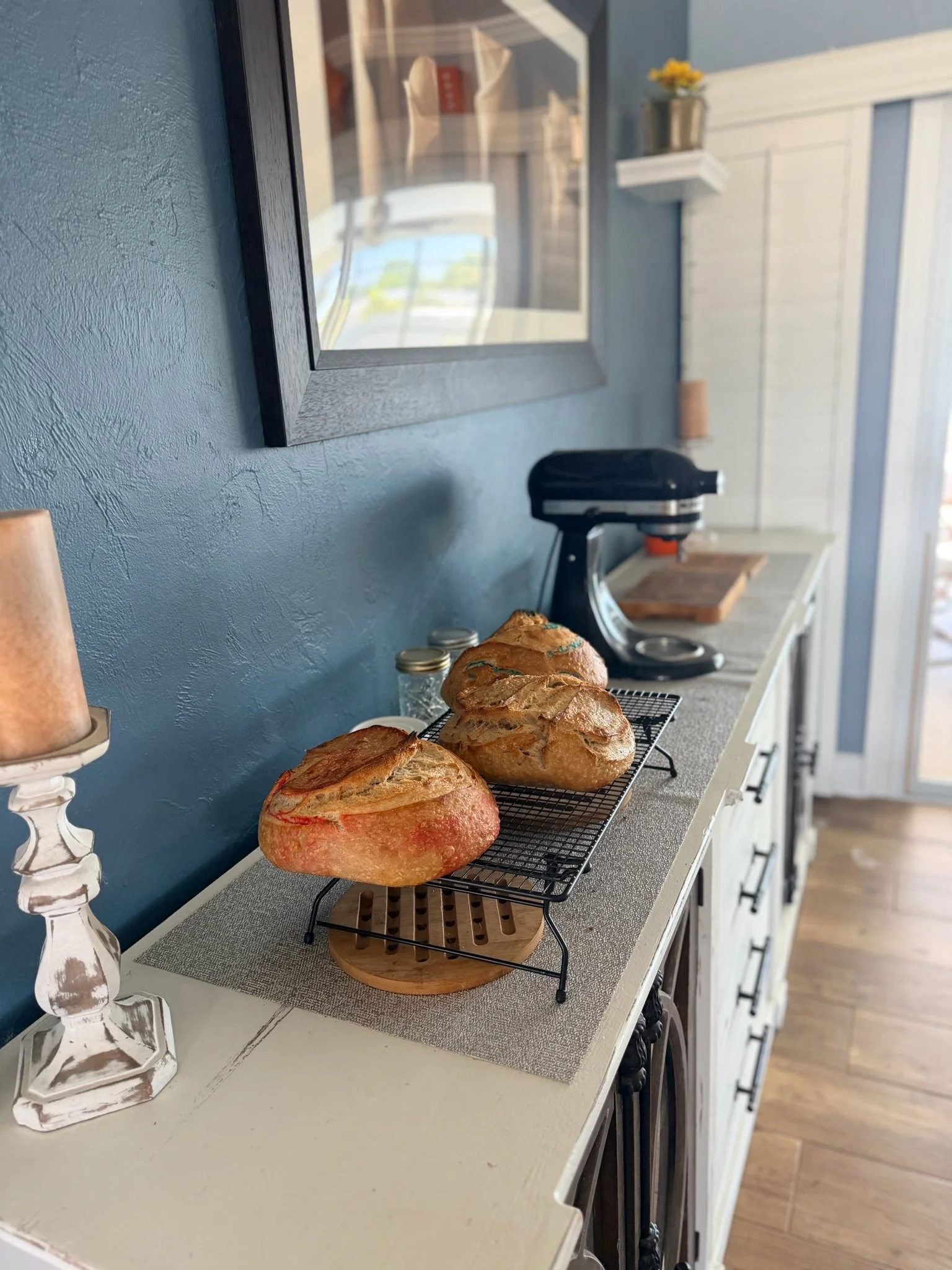 Three loaves of bread cooling on a wire rack on a kitchen counter.