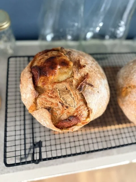 Baked bread with a golden-brown crust and toppings, resting on a wire cooling rack.