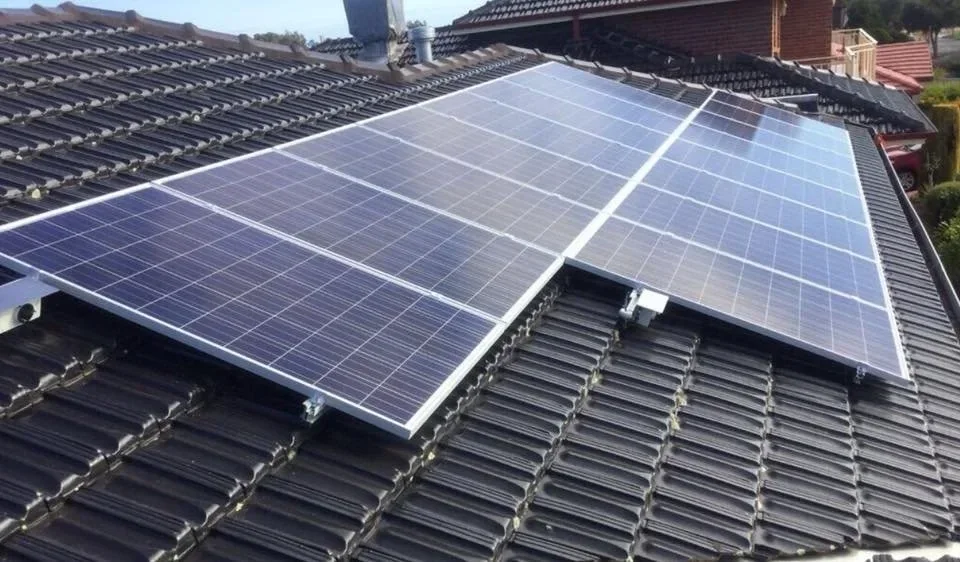 Solar panels installed on a residential rooftop with dark tiles.