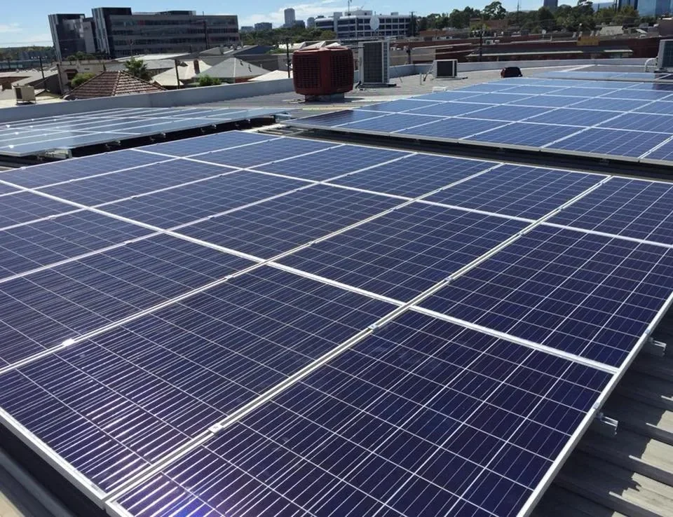 Solar panels installed on a rooftop with city buildings in the background.