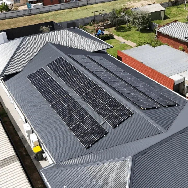 Aerial view of a house with several solar panels installed on its metal roof.