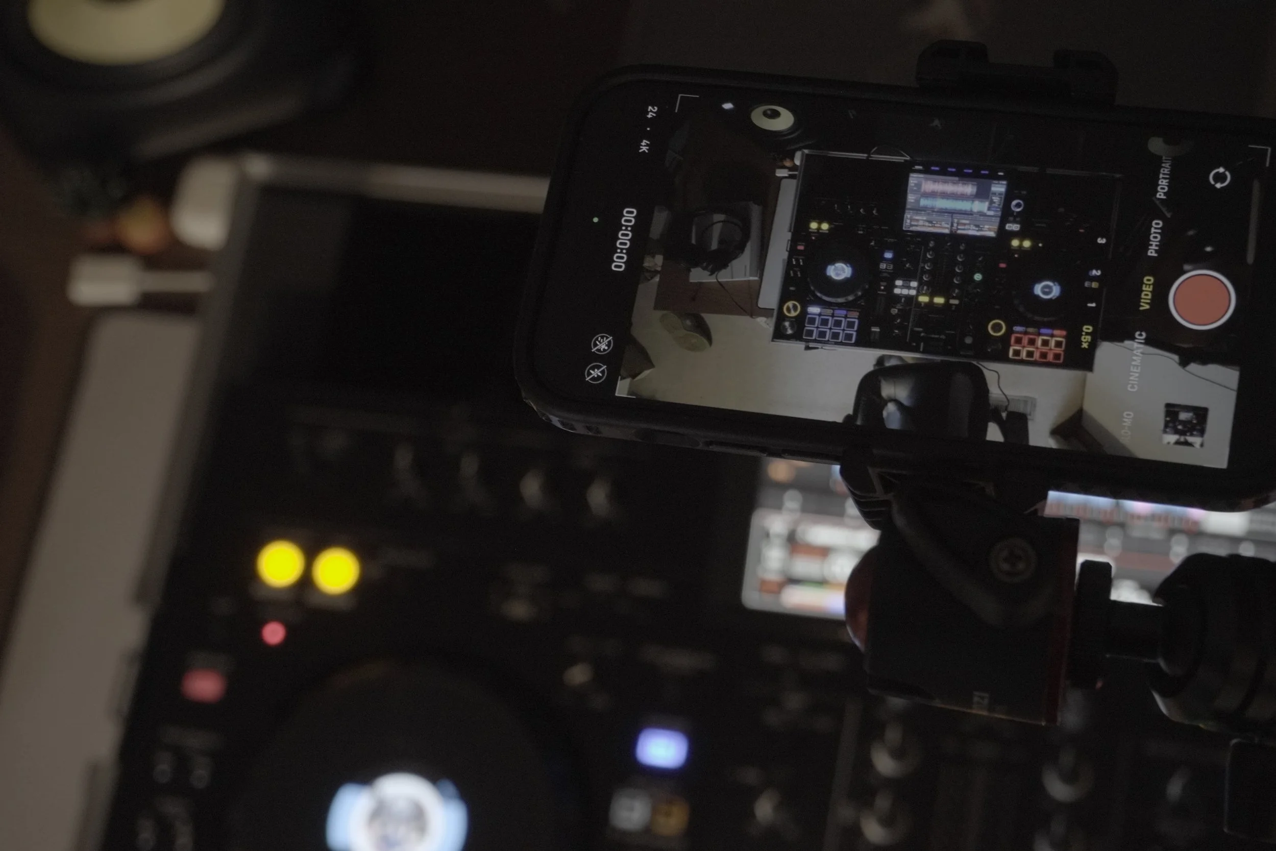 A close-up photo of a camera screen displaying a DJ setup with mixing equipment and colorful controls, in a dark environment.
