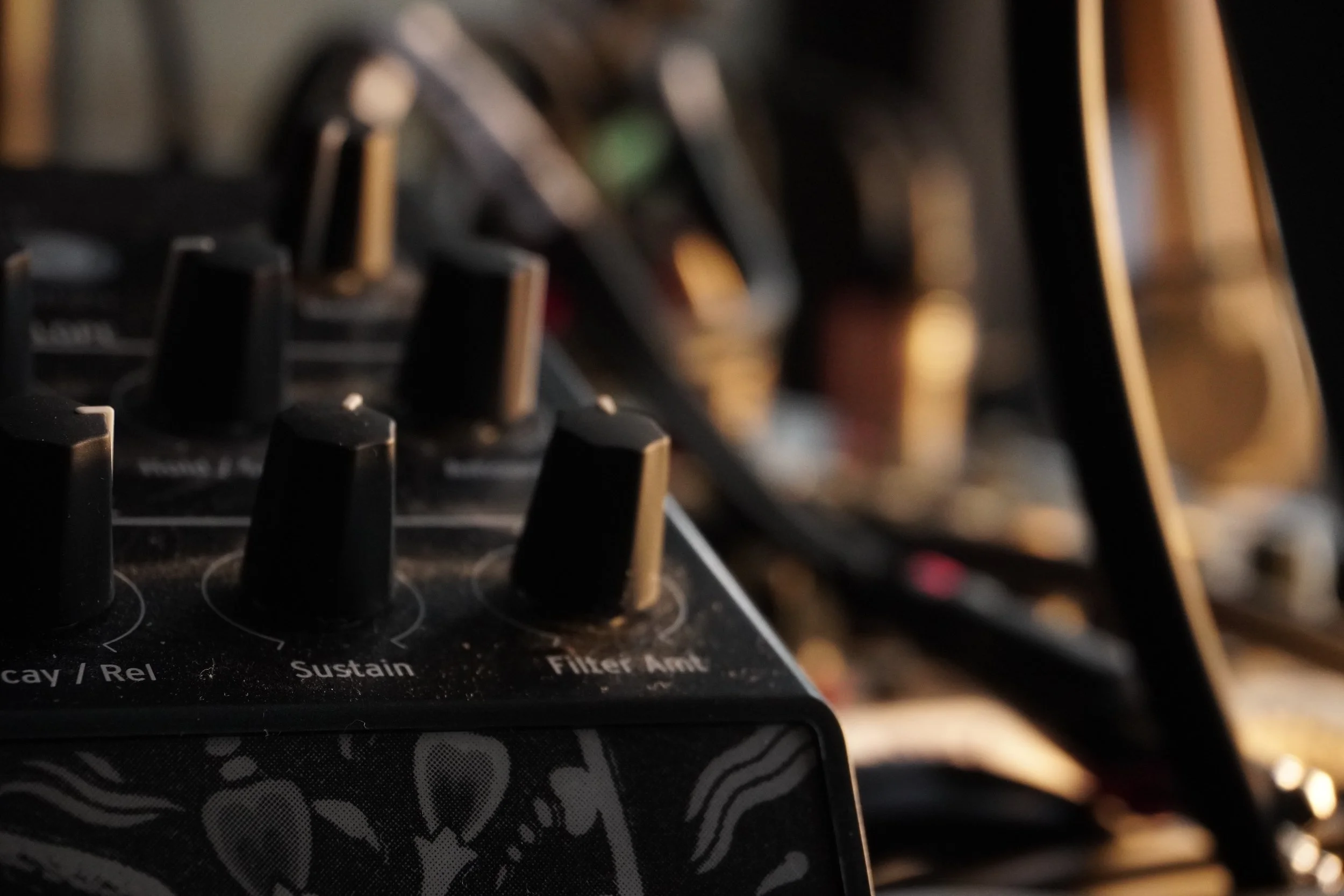 Close-up of a DJ mixer with black knobs and sliders, with some text visible on the panel, including 'Sustain' and 'Filter.'