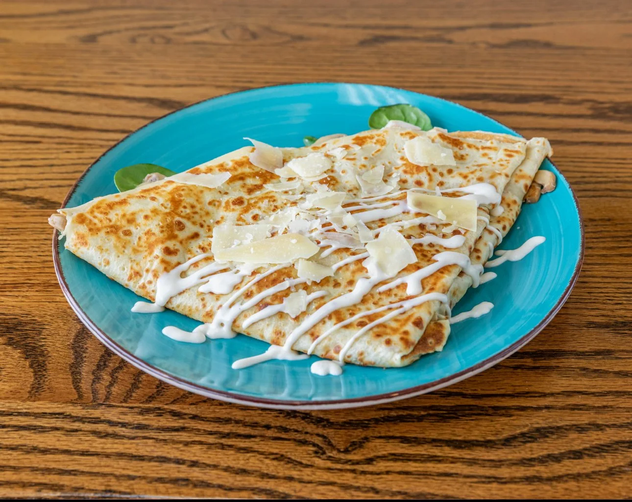A serving of lasagna on a white plate, topped with microgreens and cheese shavings, on a white marble surface.