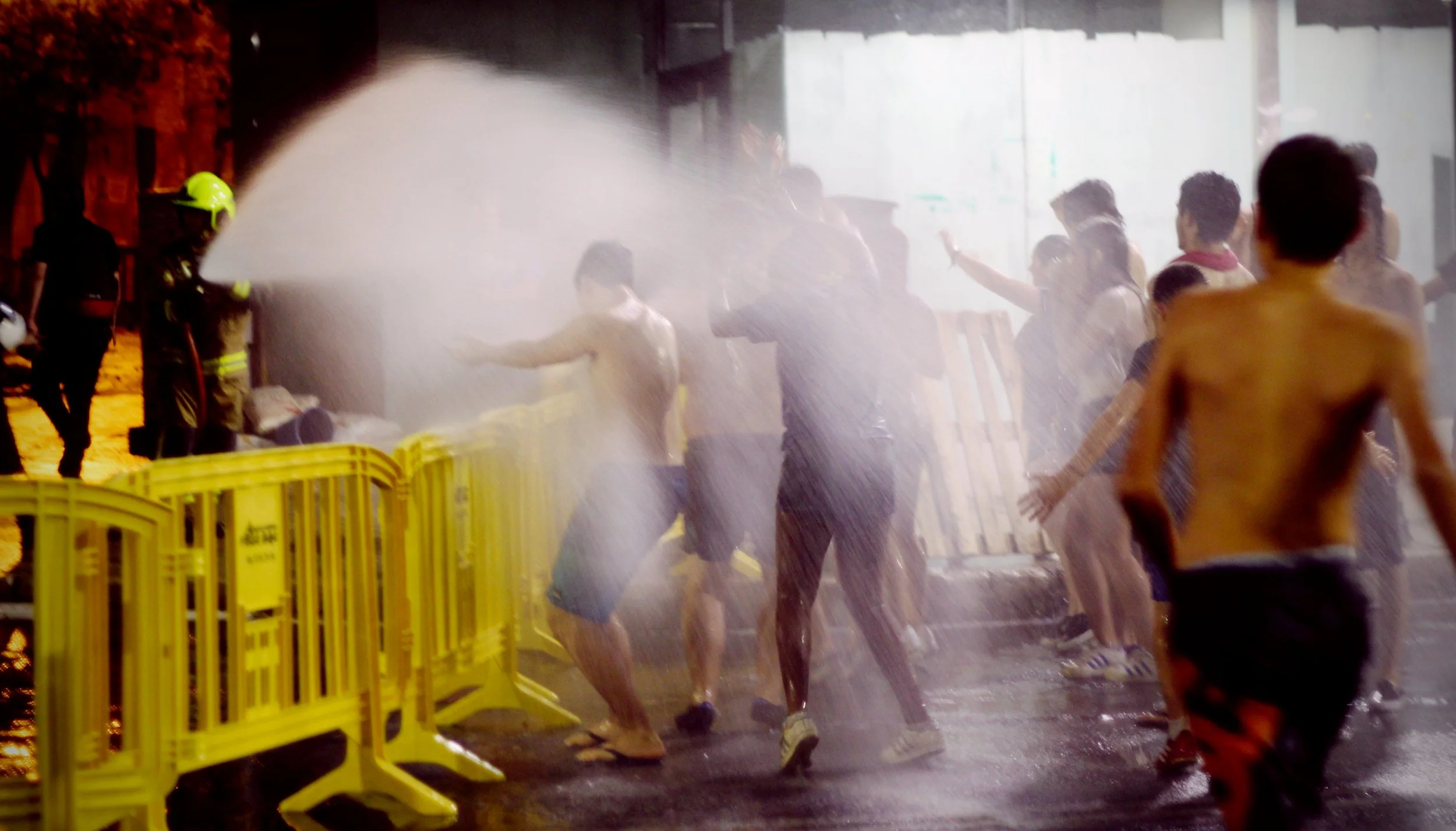 Crowd moving through water and smoke during the Cremà at Las Hogueras de Alicante.