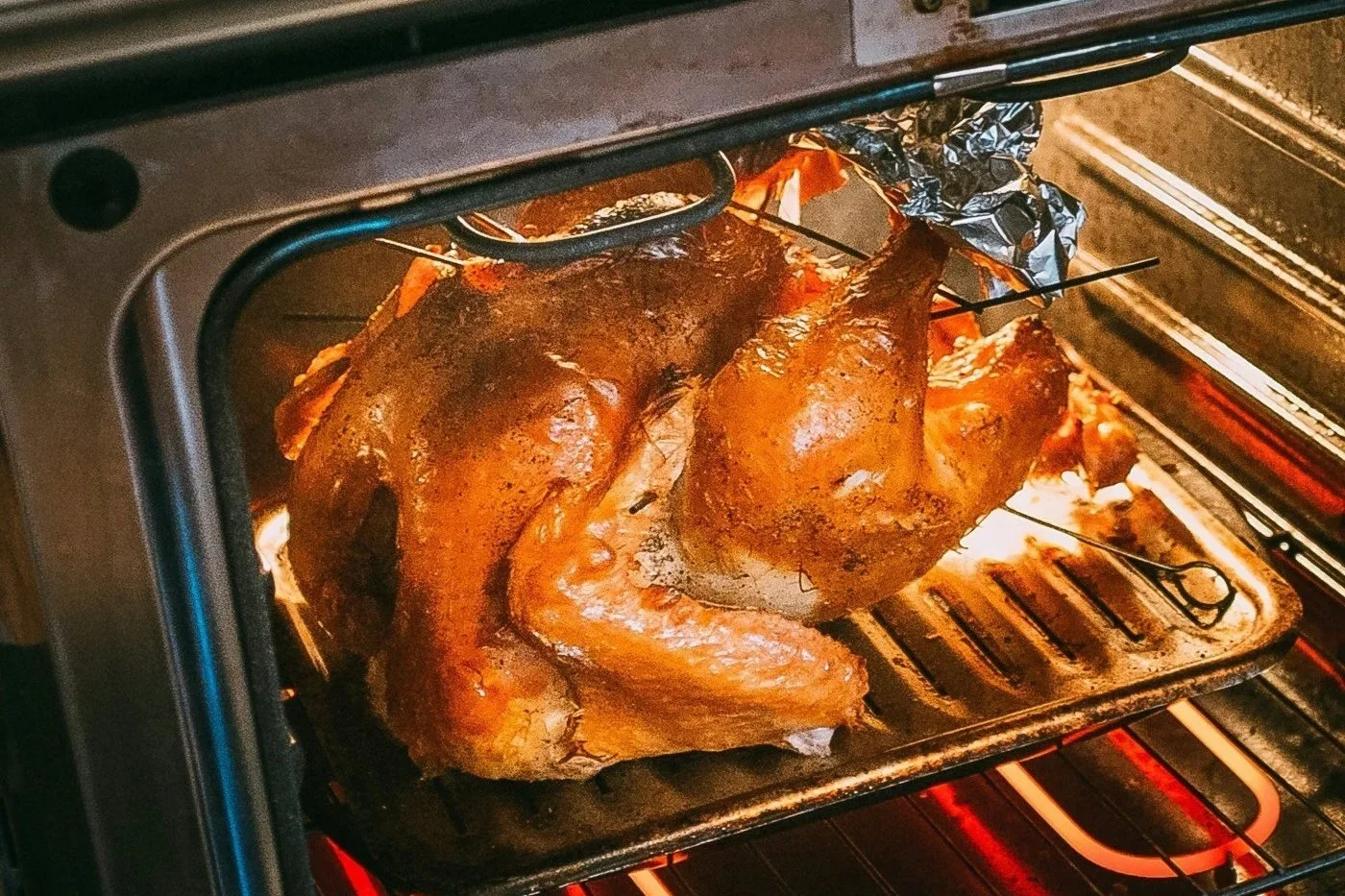 Two seasoned whole chickens roasting inside an oven on a roasting pan.