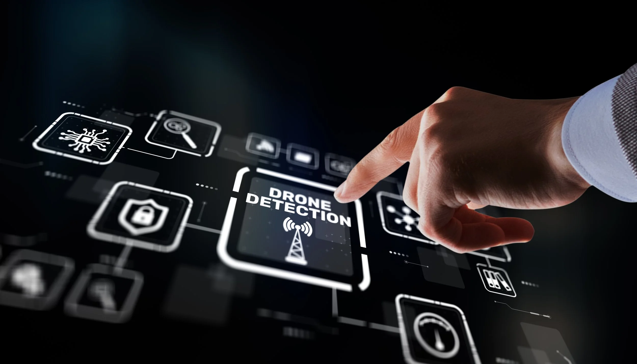 Person's hand points at a digital screen with icons related to drone detection, security, and technology.