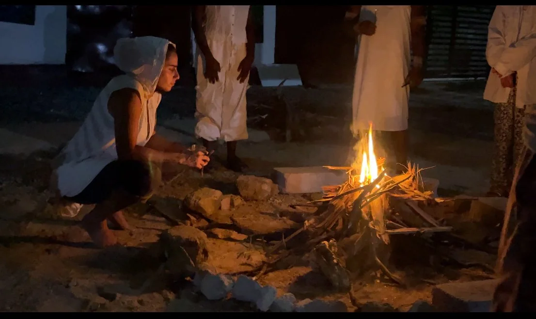 Trans people doing a ritual around a fire outdoors at night.