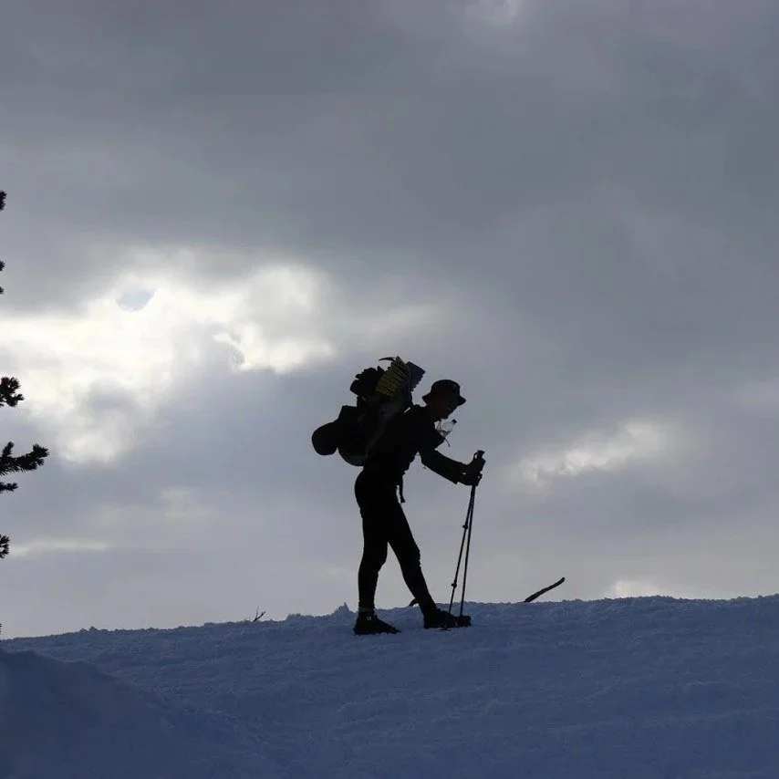 Silhouette of a person using sliding snowshoes on a winter hill in Finland
