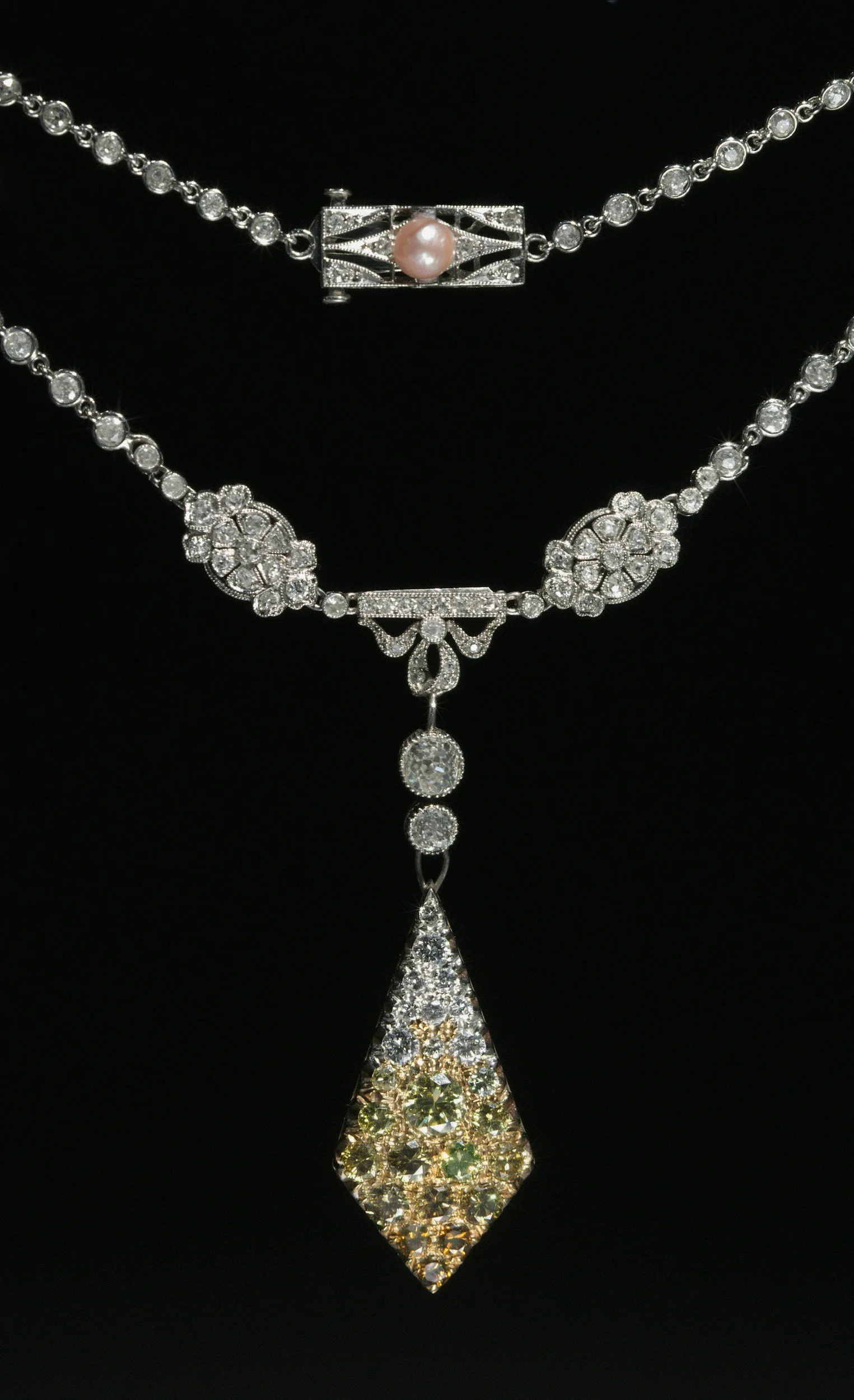 A silver necklace with diamond accents and a large diamond pendant with yellow, green, and colorless stones.