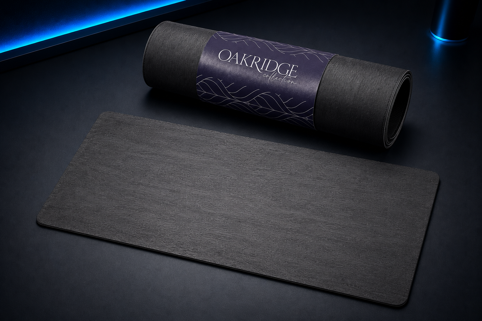 Black yoga mat with a roll of the same mat in its packaging labeled 'OAKRIDGE collection' on a dark surface.