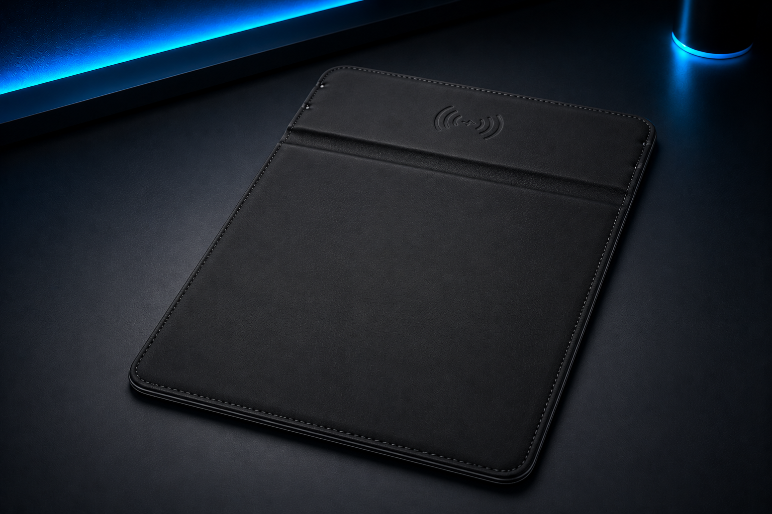 Black tablet or laptop case with a wireless charging symbol on the top, placed on a dark surface with blue accent lighting in the background.