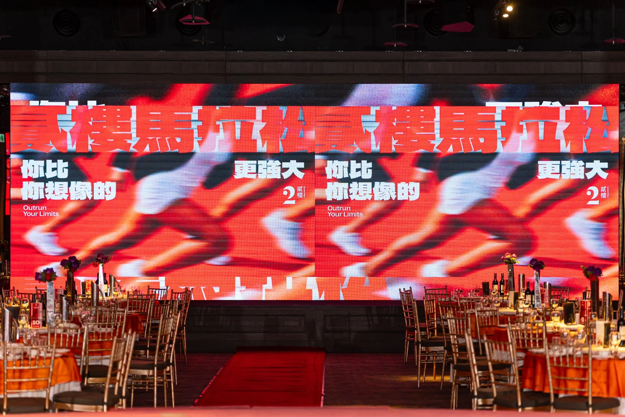 Large digital screen displaying an advertisement with red and white graphics and Chinese characters, with tables set for a banquet in the foreground.