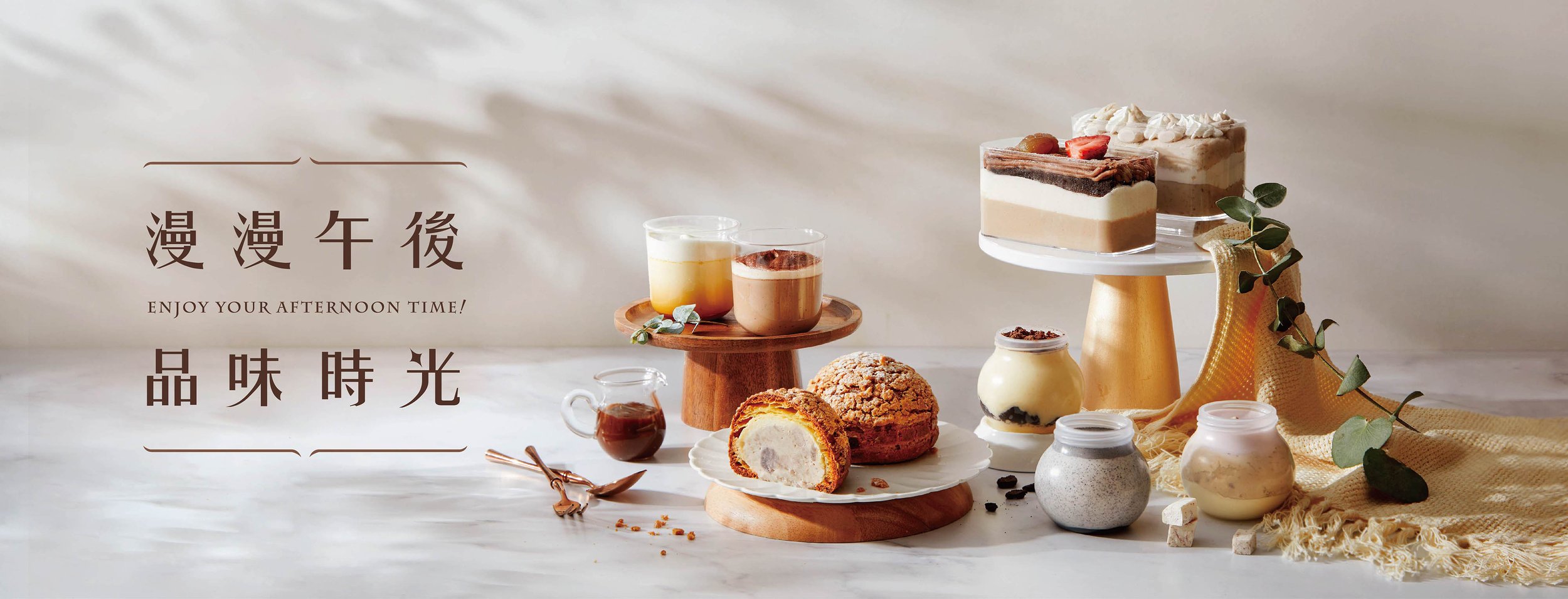 An assortment of desserts and drinks on a white marble surface, including layered cakes on a white cake stand, cookies on a wooden tray, and various beverages in glasses and jars, with a beige knit cloth and greenery. Chinese characters and the phras