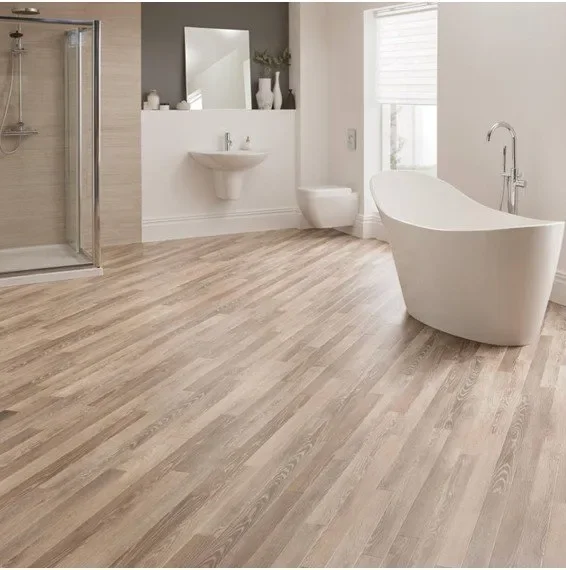Modern bathroom with a standalone bathtub, a wall-mounted sink, and a walk-in shower with a glass door. Light wood flooring and natural light from a window.