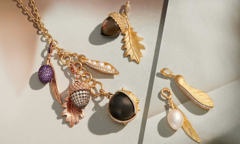Gold necklace with purple and pearl charms, plus leaf, acorn, and berry pendants, and matching gold earring with leaf and pearl charms.