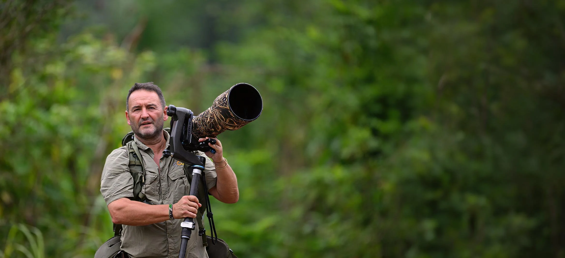 Un hombre en la selva sostiene una cámara de telefoto
