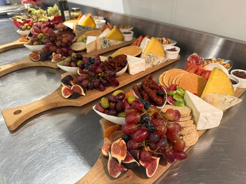 Cheese and fruit platter with grapes, figs, crackers, and various cheeses on wooden boards at the Fox, Cork & Feathers in Dolgellau