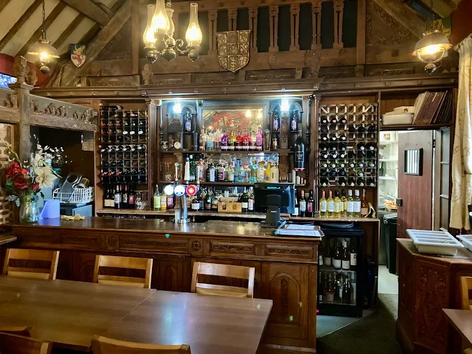 Interior of a Y Sopsan bar in Dolgellau, with a wooden counter, wine bottles on display, and hanging lamps, with a dining table and chairs in the foreground.