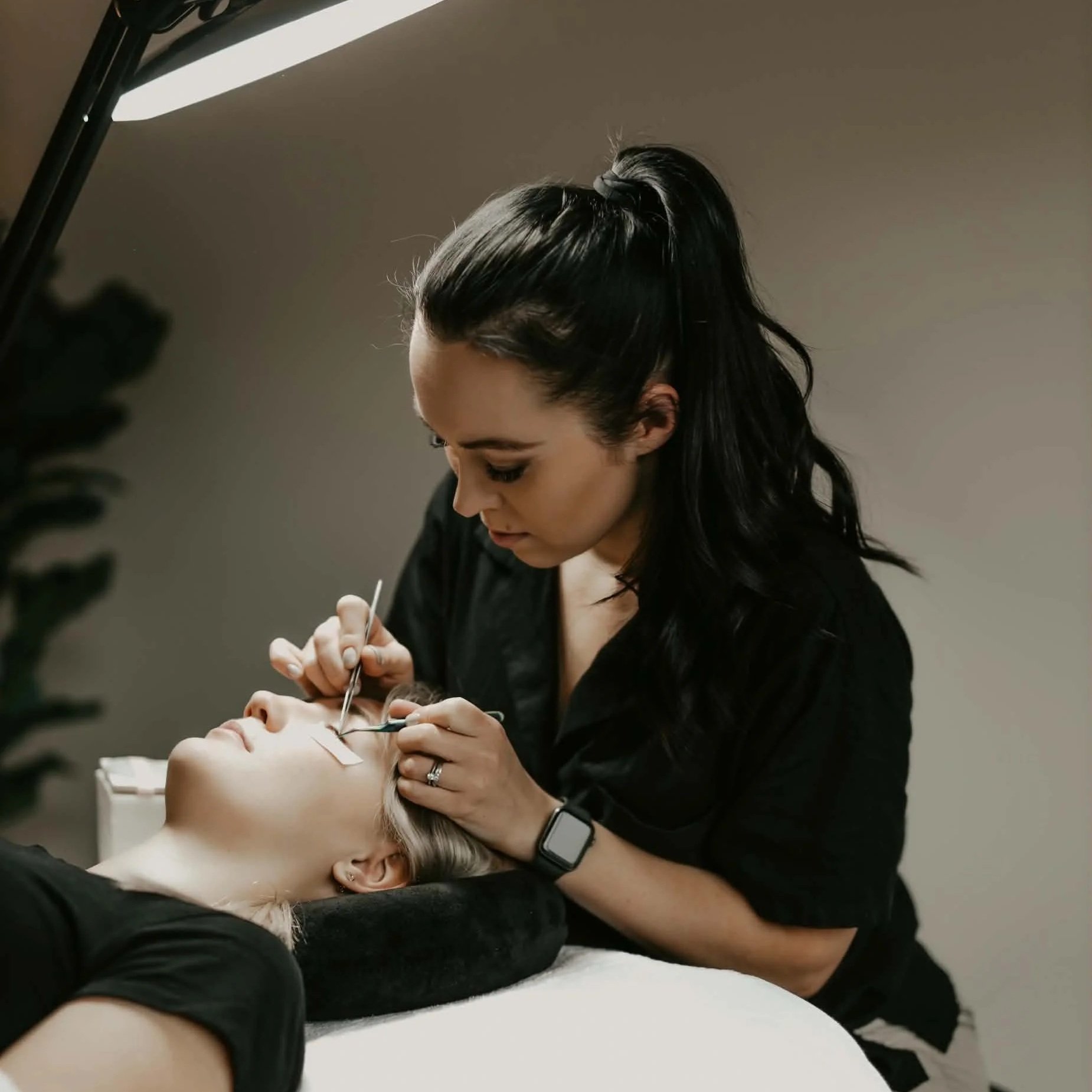 Lash technician applying eyelash extensions to a client in a professional lash studio