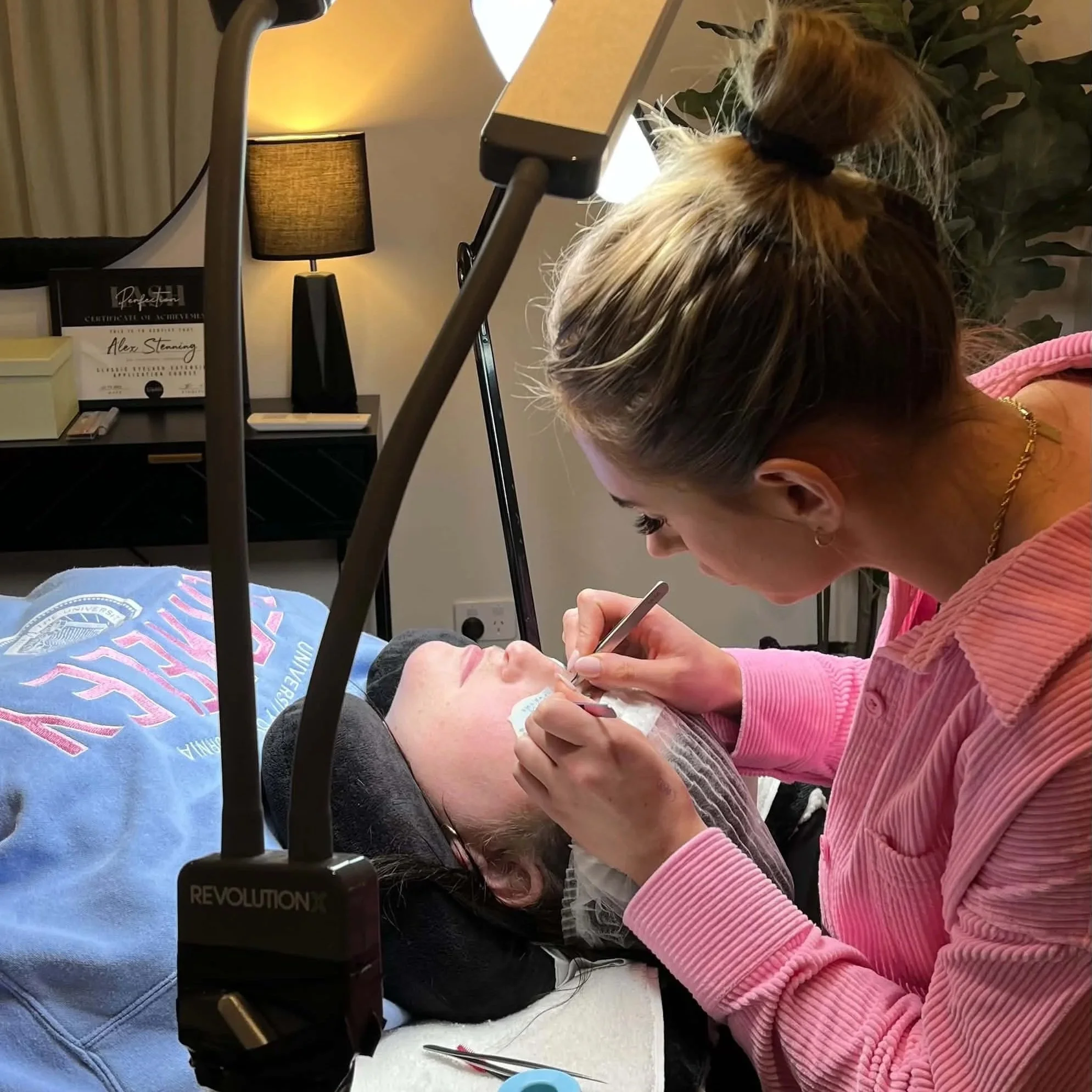 Beginner lash student practising professional eyelash extension application on a live model