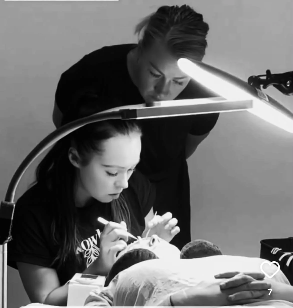 Professional lash educator applying eyelash extensions to a client using safe professional technique