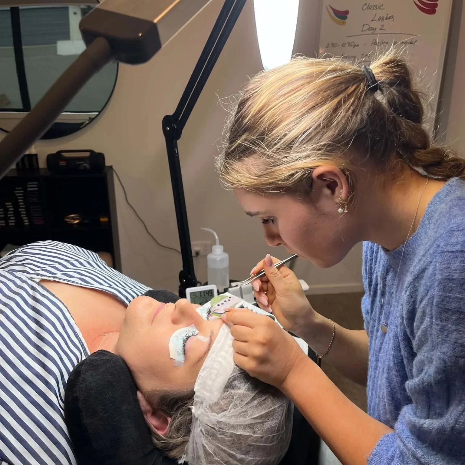 Beginner lash student practising eyelash extension application on a live model during professional lash training