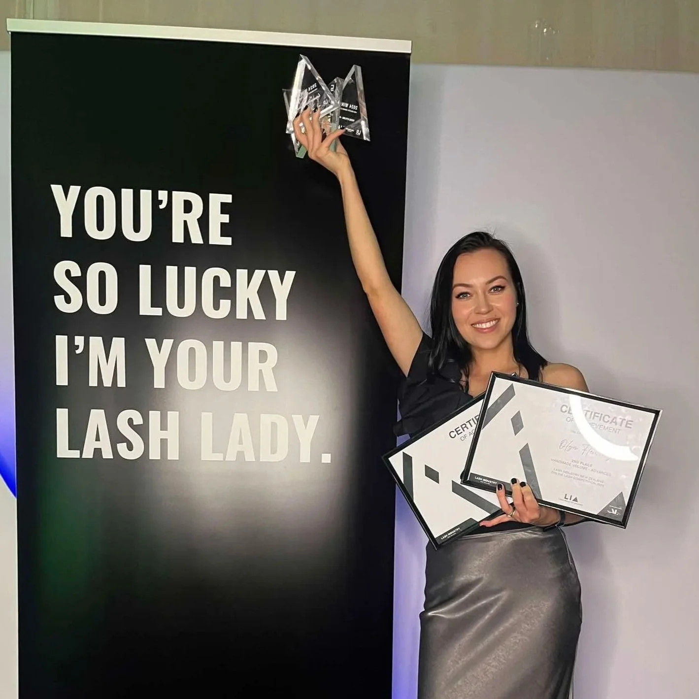 Olga Fleming holding lash industry awards and certificates at the New Zealand Lash Industry Awards.