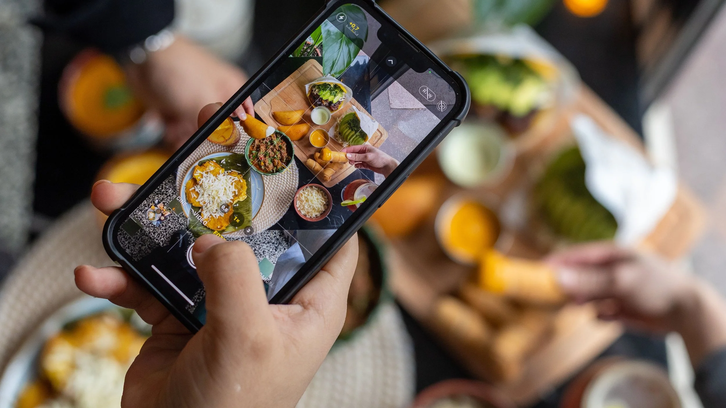 Persona tomando una foto de una comida en una mesa con su teléfono móvil.