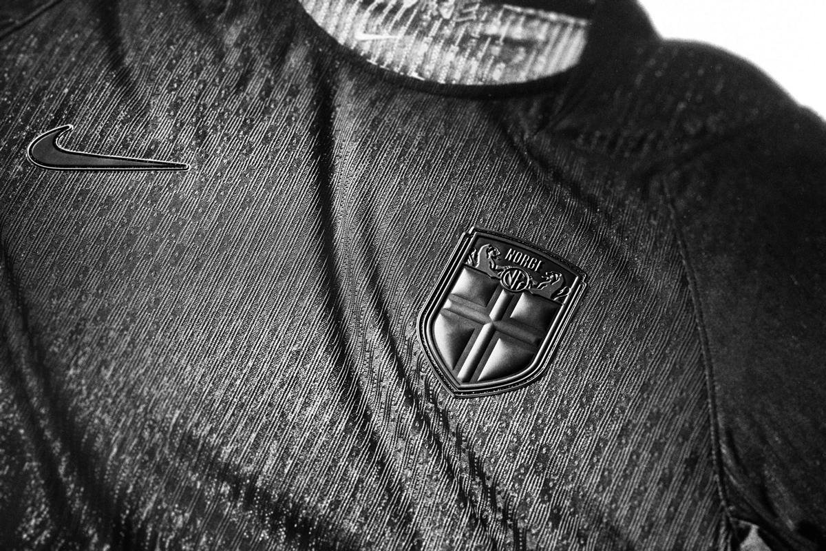 Close-up of a black Nike sports jacket with a badge featuring a cross, a lion, and text, and a Nike logo pin.