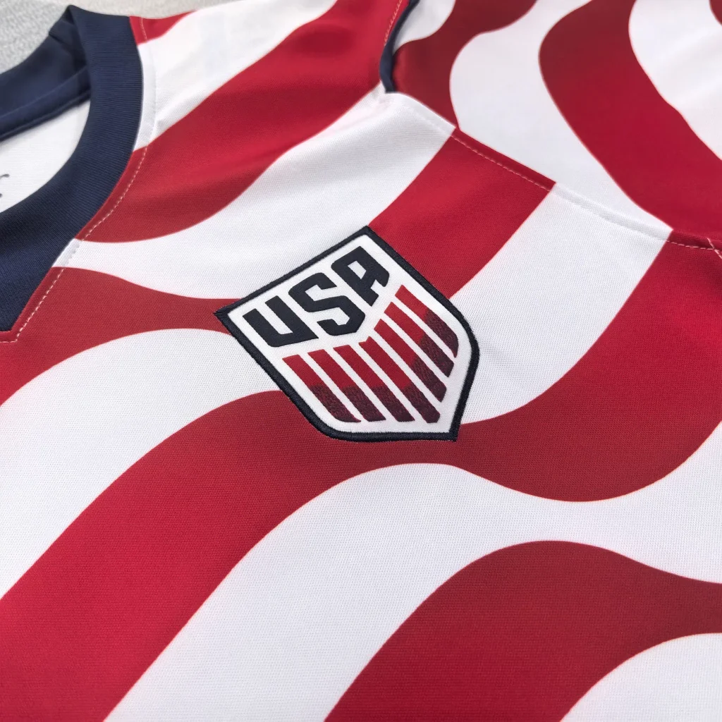 Close-up of a sports jersey with red and white stripes and a USA shield logo.