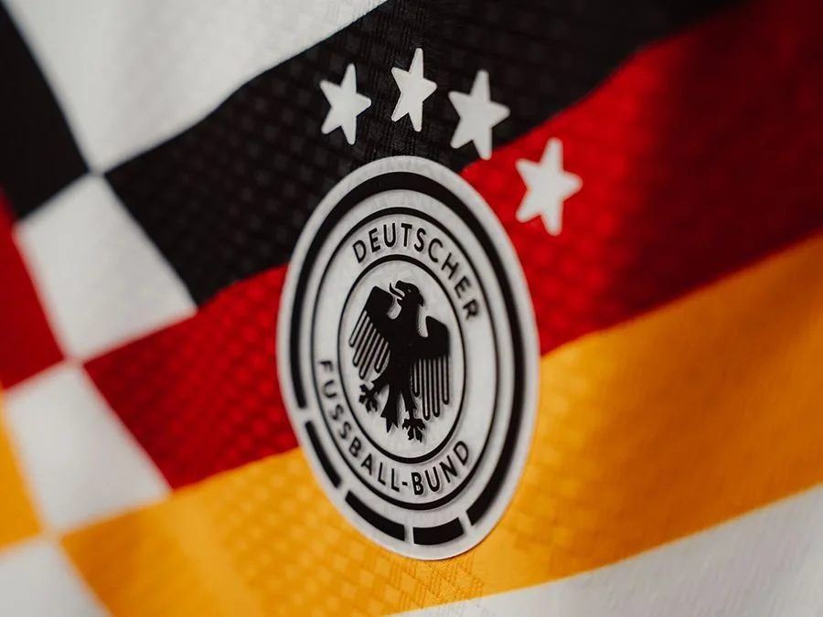 Close-up of the German national soccer team logo on a fabric with the German flag colors and pattern.