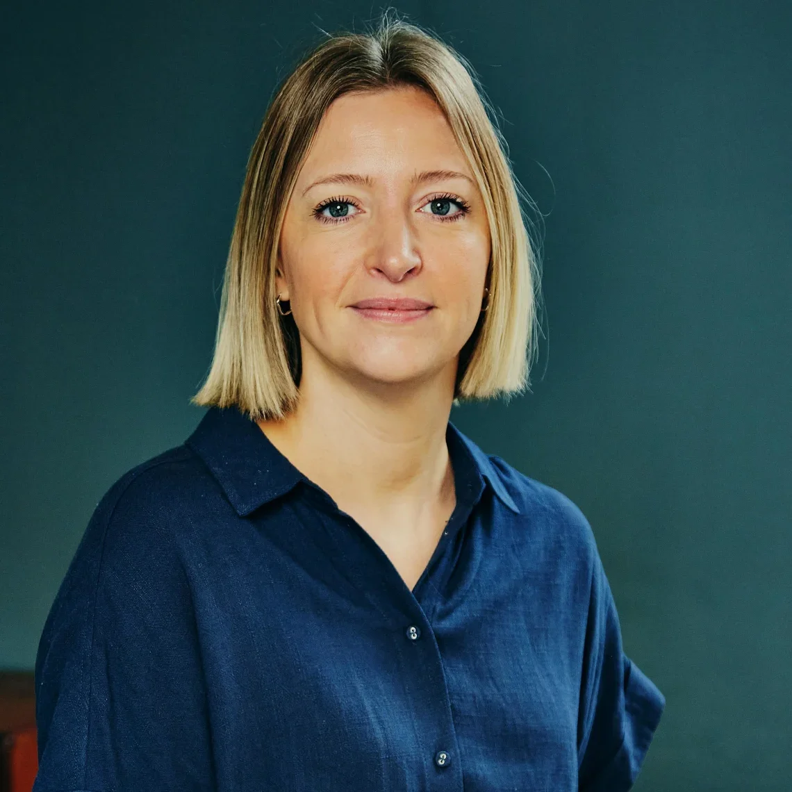 Portrait of a woman with blonde hair in a blue shirt against a dark background