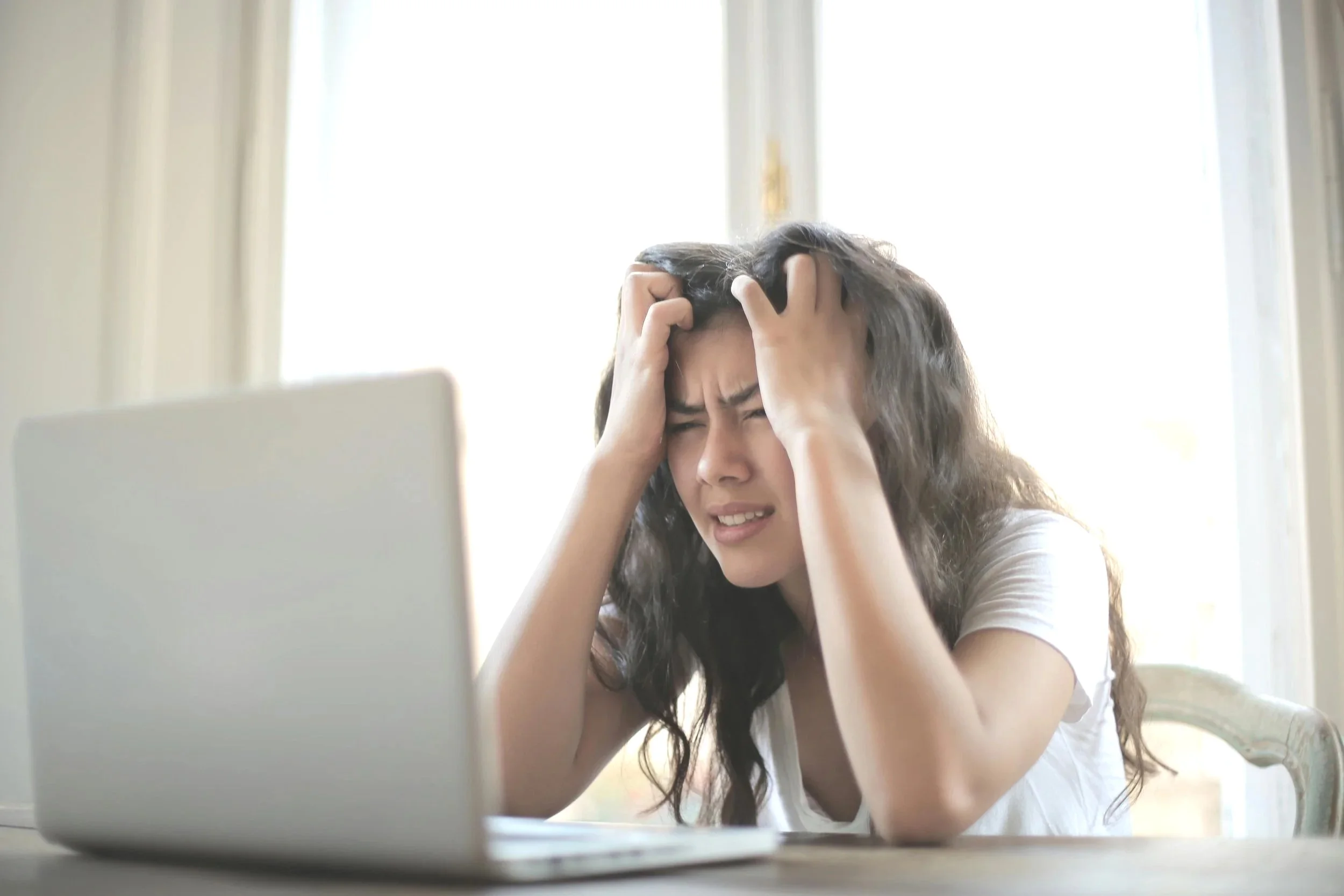 Woman holding her head due to migraine. From the article "Understanding Different Types of Headaches & Their Treatments".