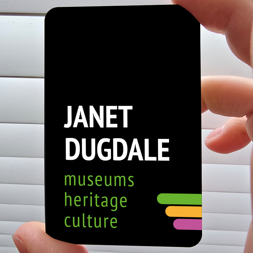 An A6 business card in black with white writing on saying Janet Dugdale and underneath text saying museums heritage and culture in a vibrant green. On the bottom right are three rounded rectangles in green, yellow and pink