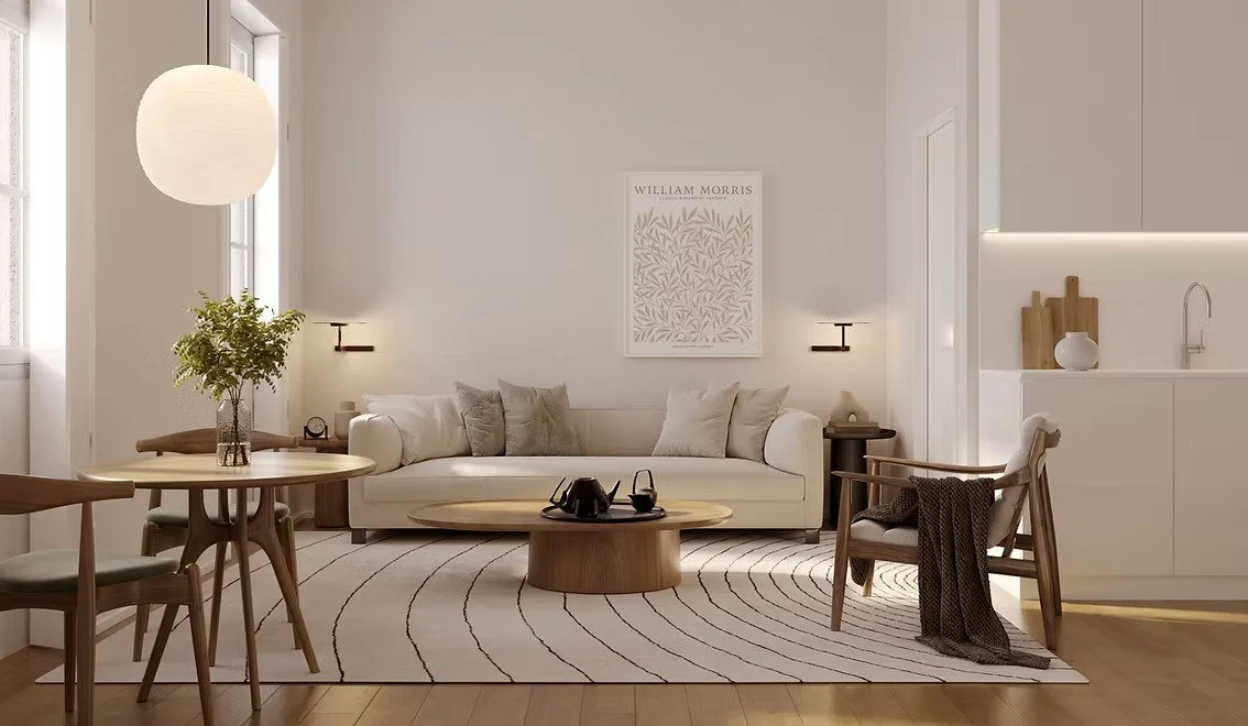 A modern, minimalist living room with a white couch, wooden coffee table, and a round dining table with chairs. Decor includes a potted plant, wall art, and subtle lighting fixtures.