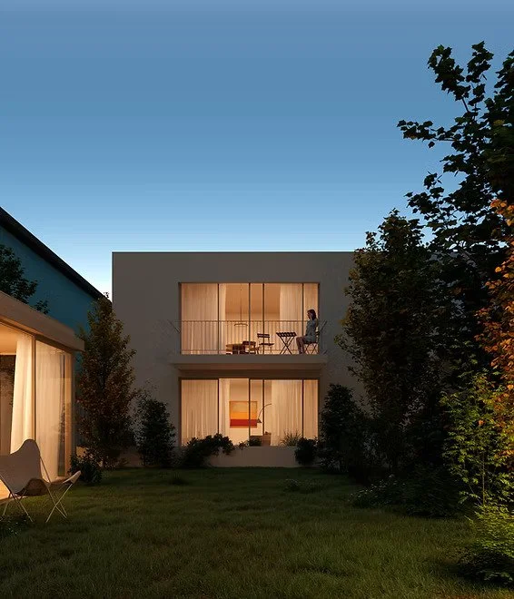 A modern two-story house with large windows, surrounded by green trees and grass, at dusk with an evening sky.