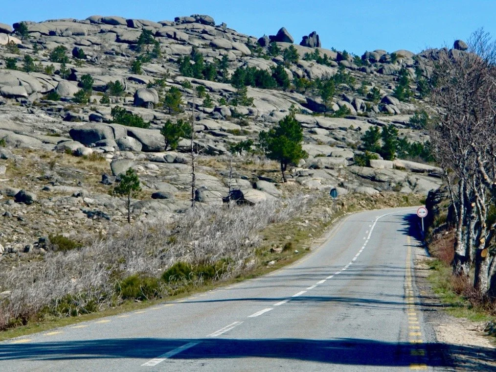 A film and photo location in Portugal from walnut films, A winding mountain road with a no-entry sign, surrounded by rocky terrain and sparse pine trees under a clear blue sky.
