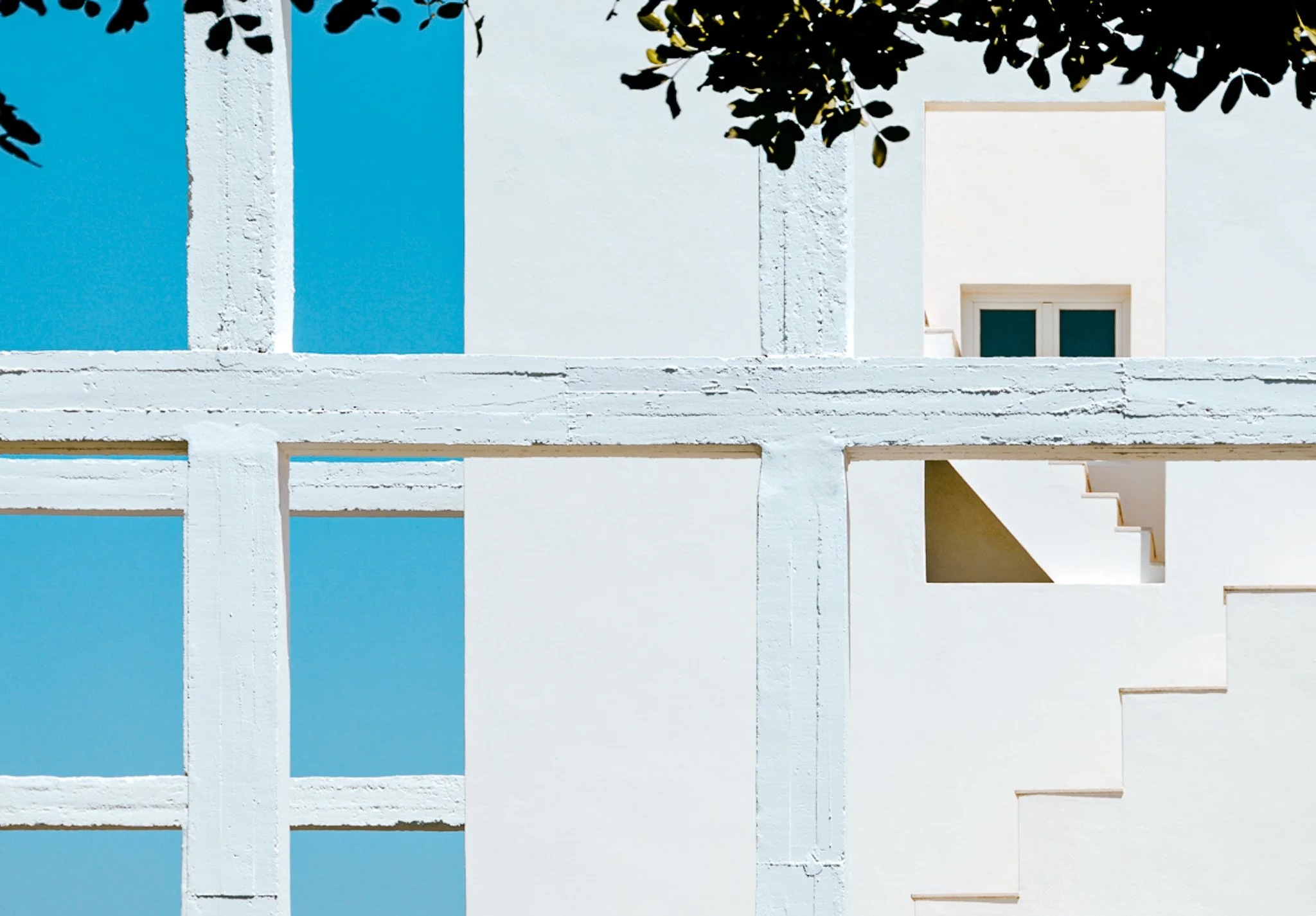 A film and photo location in Portugal from walnut films, White building with blue accents, green window, and shadows of tree leaves at the top.