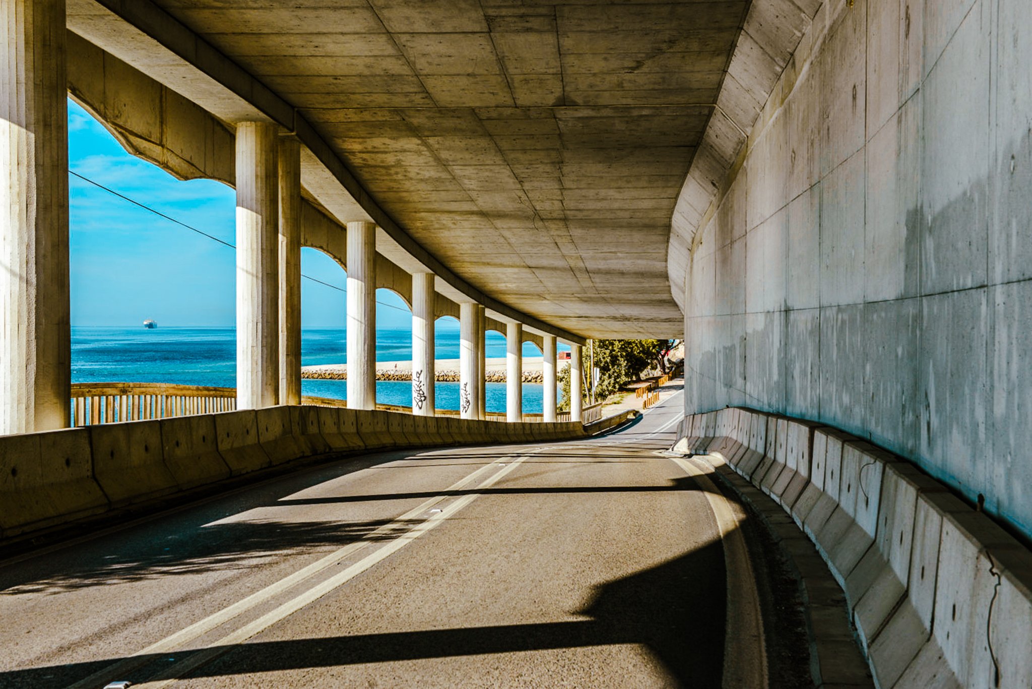 A film and photo location in Portugal from walnut films, Underground highway tunnel with concrete walls and ceiling, view towards city and ocean in the distance through the openings, 