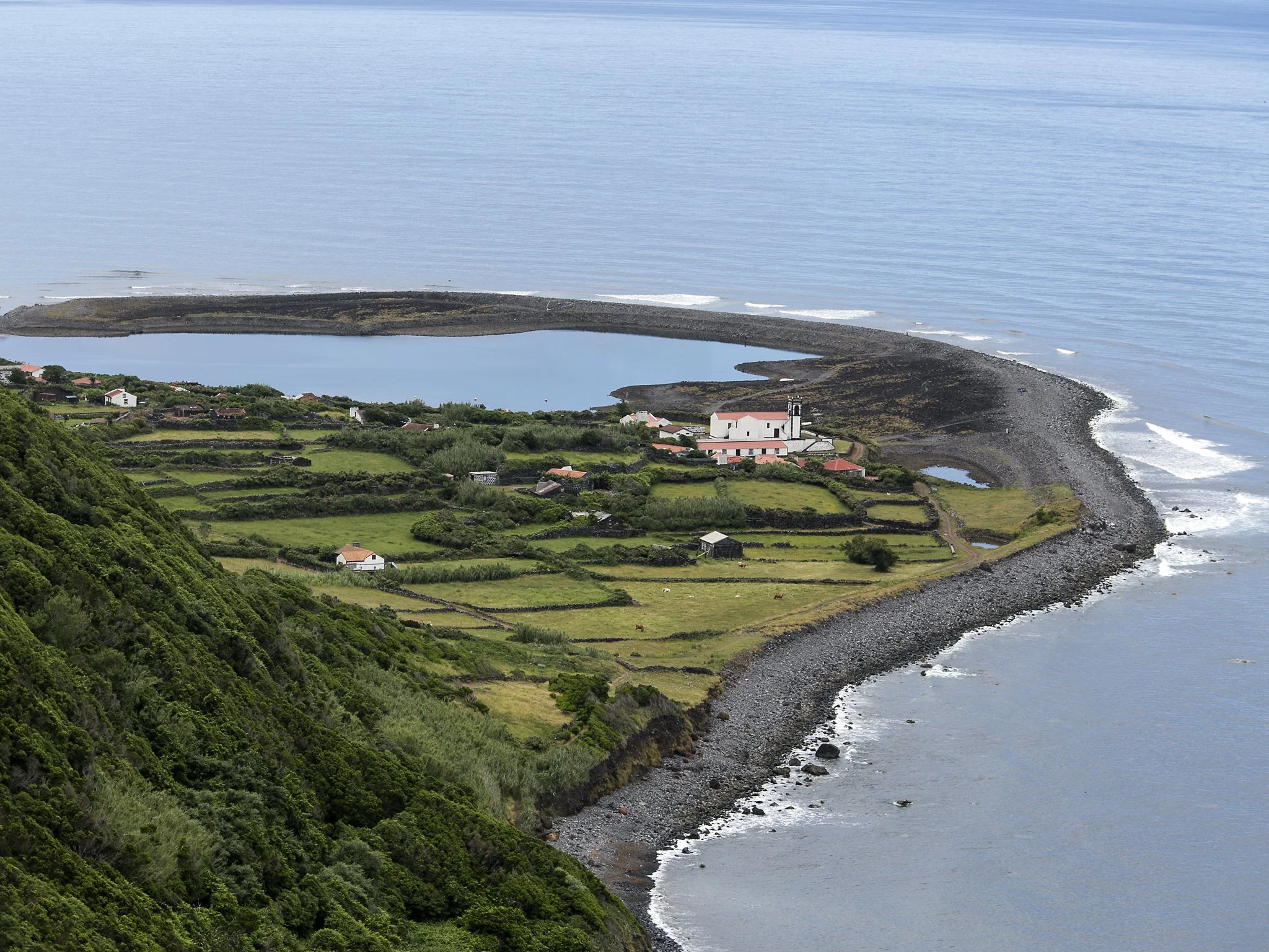 A film and photo location in Portugal from walnut films, A coastal landscape with a small village, a beach, and a sea water lagoon separated from the ocean by a rocky shoreline, view from an elevated position.