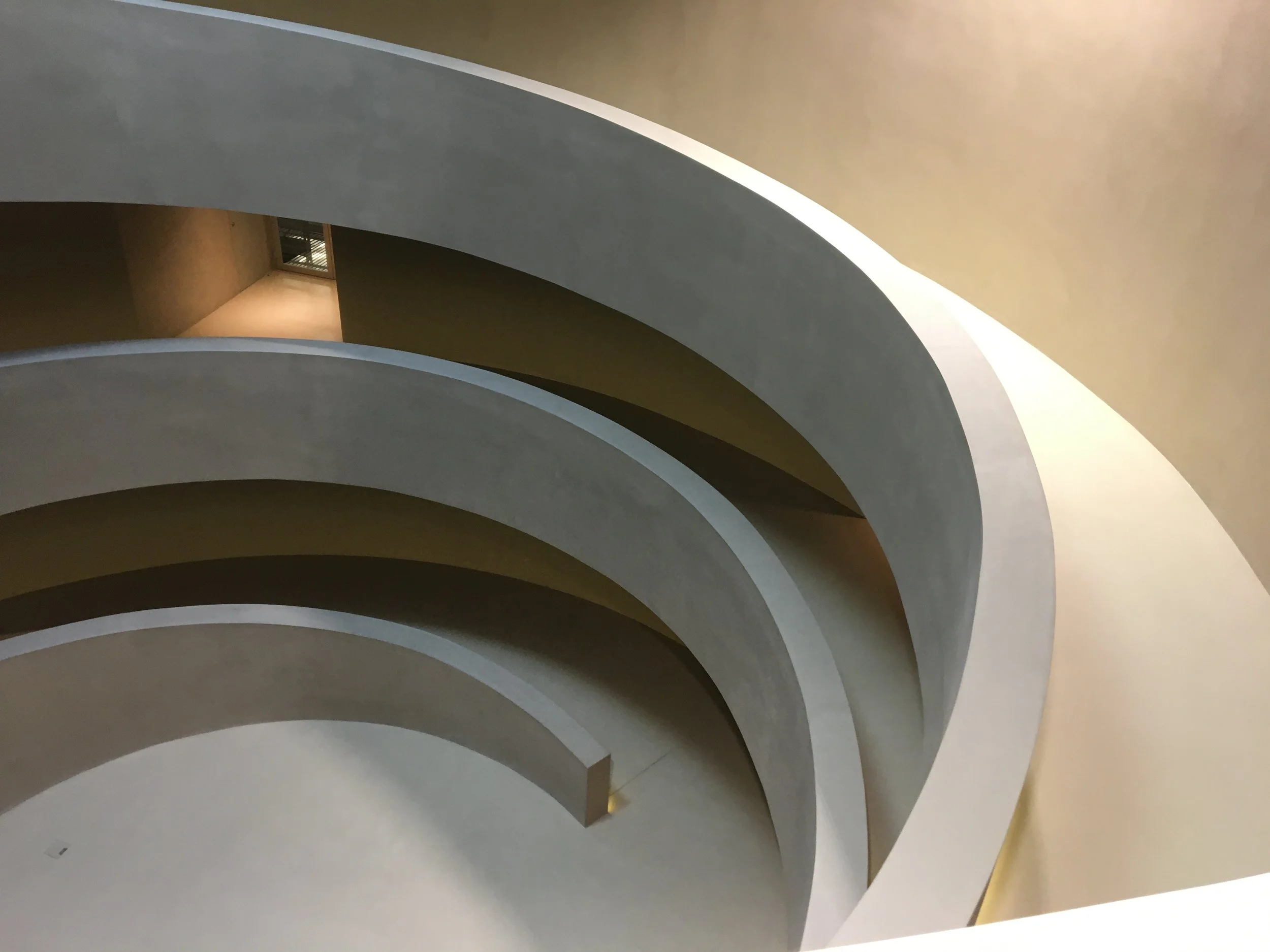 A film and photo location in Portugal from walnut films, Interior view of a modern, spiral staircase with smooth, curved steps and minimalist design, captured from a central angle.